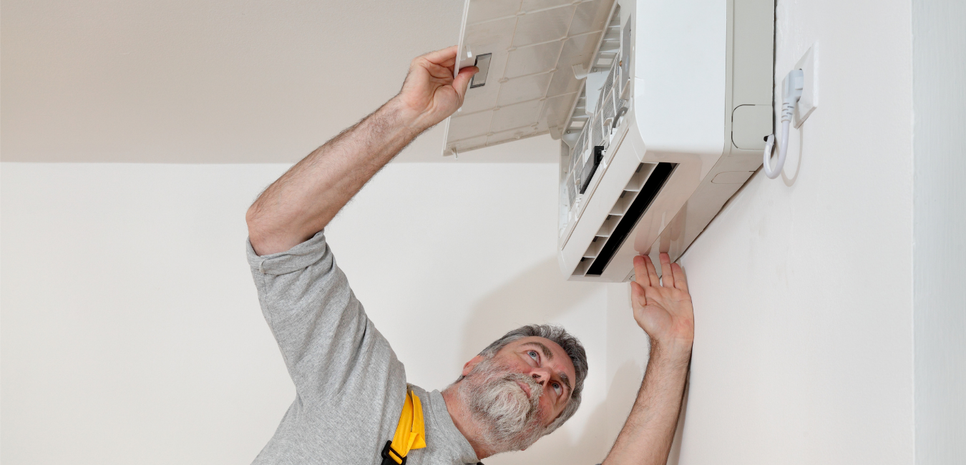 Majstor pregledava klima uređaj na zidu.