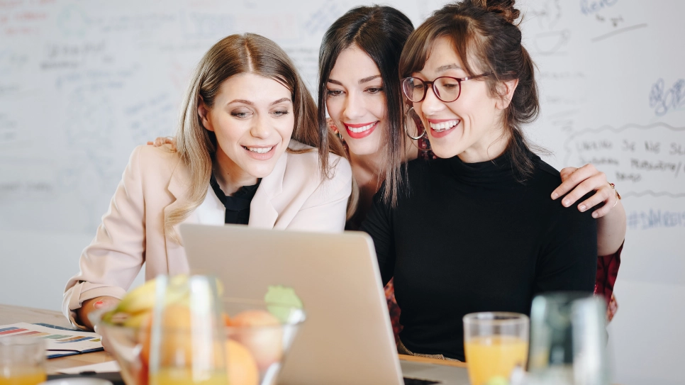 Tri žene zadovoljno gledaju ponudu na kompjuteru.