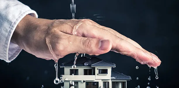 Minijaturna kuća koju ruka štiti od curenja vode.