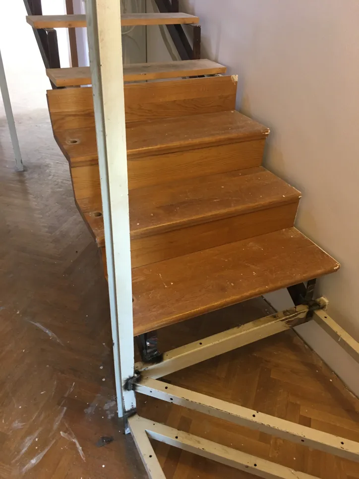 Djelomično demontirana drvena stepenica s nedostajućim stepenicama i izloženim metalnim okvirom.