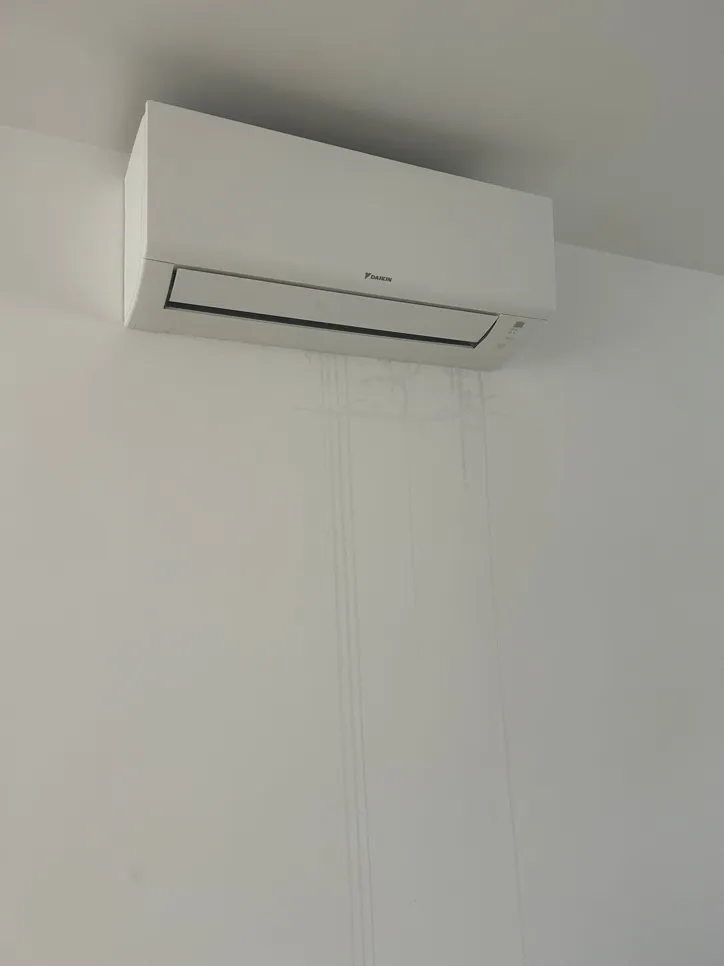 Air conditioner with visible water stains on the wall below, indicating a potential leak problem.