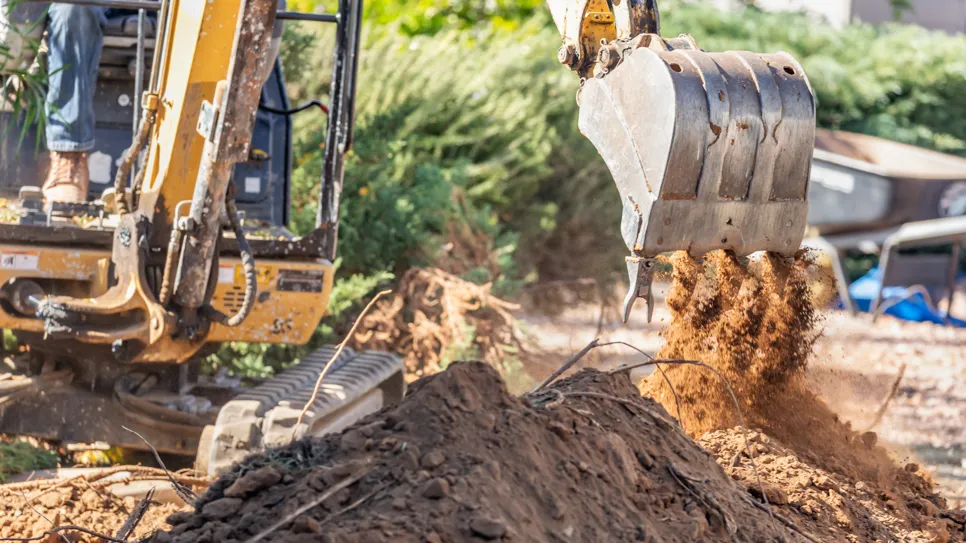 Bager u radu kopa zemlju na gradilištu.