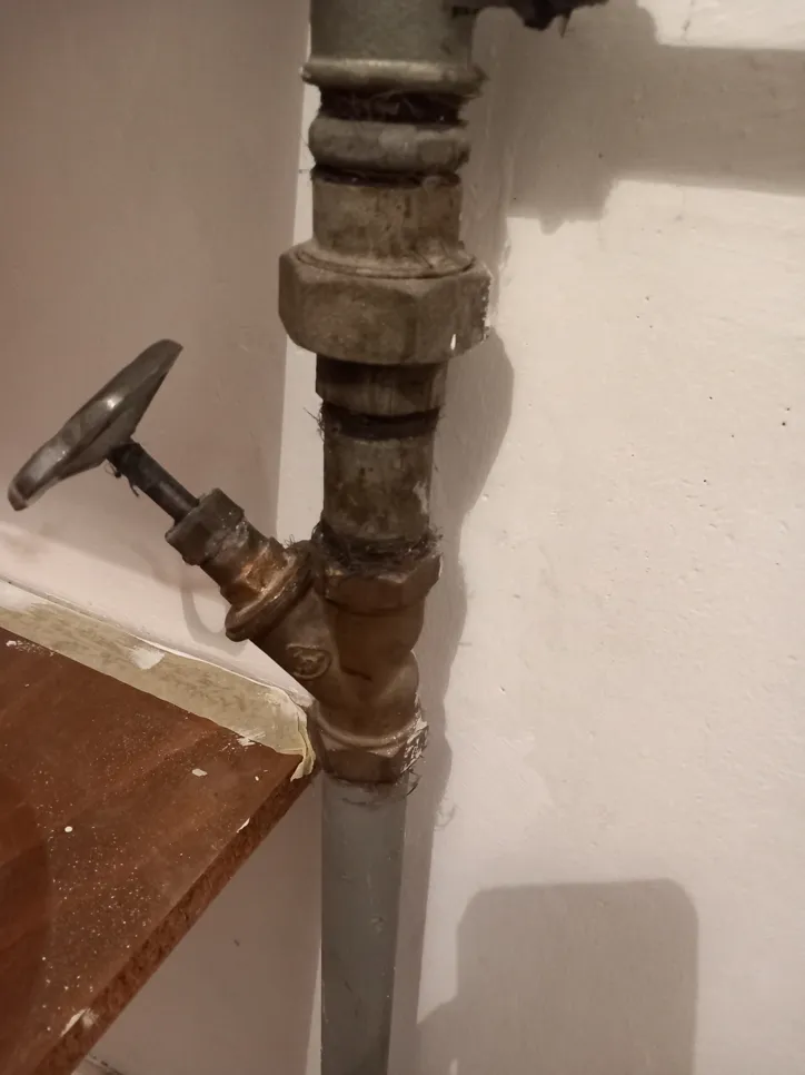 A corroded water valve on a metal pipe displaying signs of rust and wear, suggesting potential leakage.