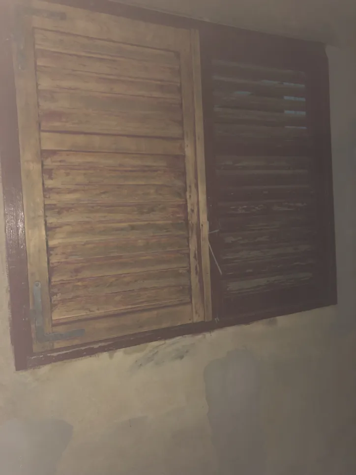 Aged wooden window shutters showing signs of weathering and discoloration indoors.