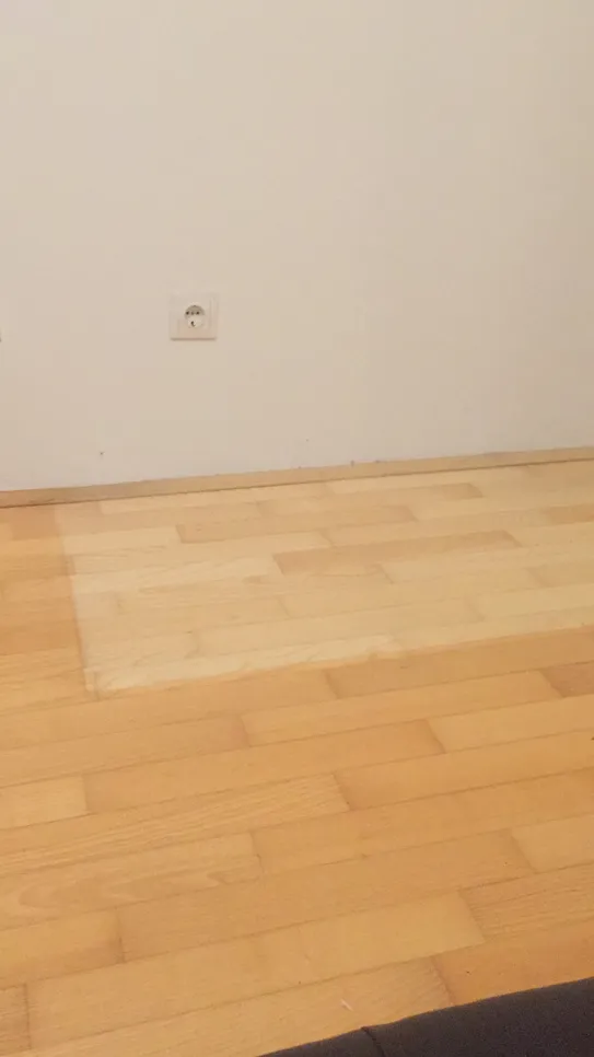 Area of wooden floor showing noticeable discoloration and fading compared to surrounding floorboards.