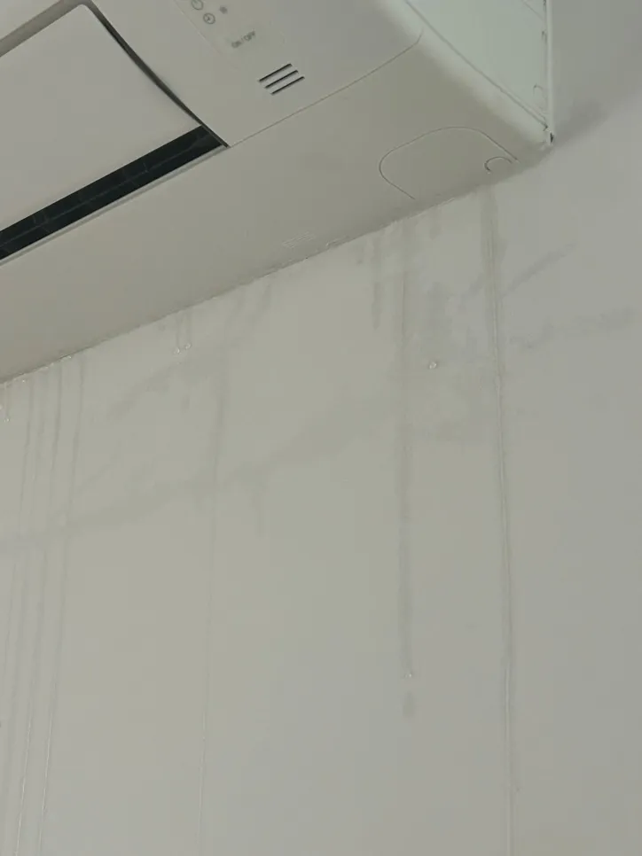 Water stains under an air conditioner indicate possible leakage or condensation issues on the wall.