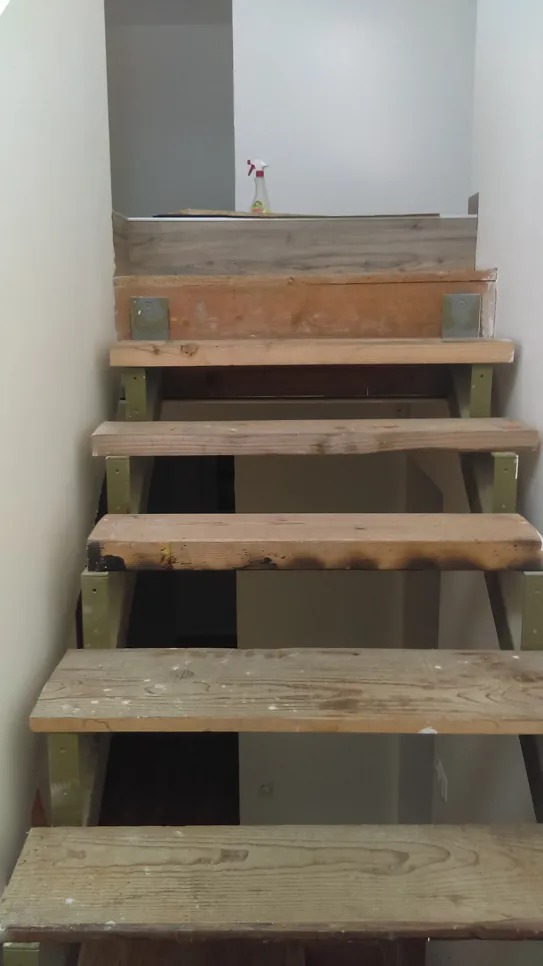 Drvene stepenice s nepravilnim koracima i nedostajućom gornjom daskom, što predstavlja opasnost za sigurnost.