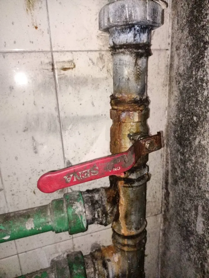 A rusty valve on a corroded water pipe, showing signs of leakage and need for repair.