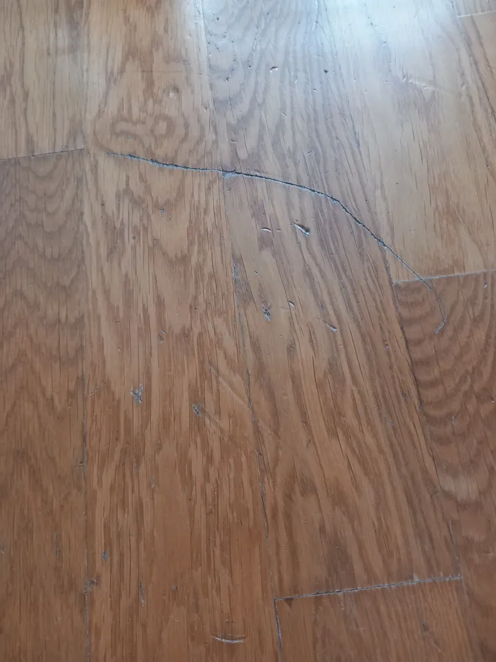 Kratak pregled oguljene drvene podloge koja pokazuje uočljivo trošenje i oštećenje površine.