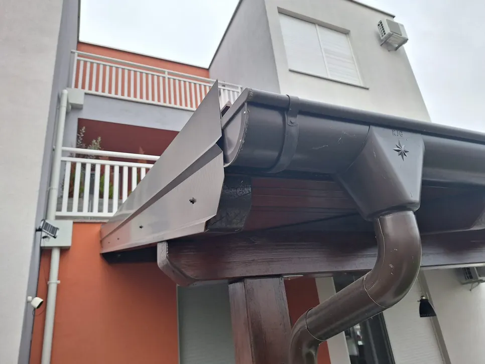 Bliski pogled na sustav kišnih žljebova s vidljivim curenjem na stambenoj zgradi.