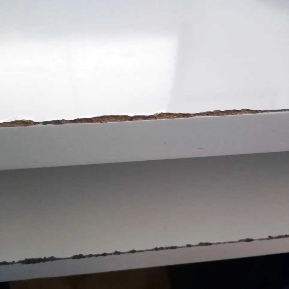 Kratki pregled bijele radne površine s oštećenim rubovima koji otkrivaju temeljni materijal.