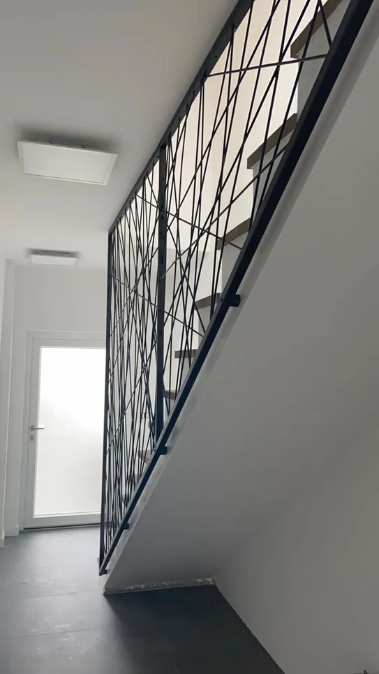 Suvremena stepenica sadrži složenu crnu metalnu ogradu i elegantan dizajn.