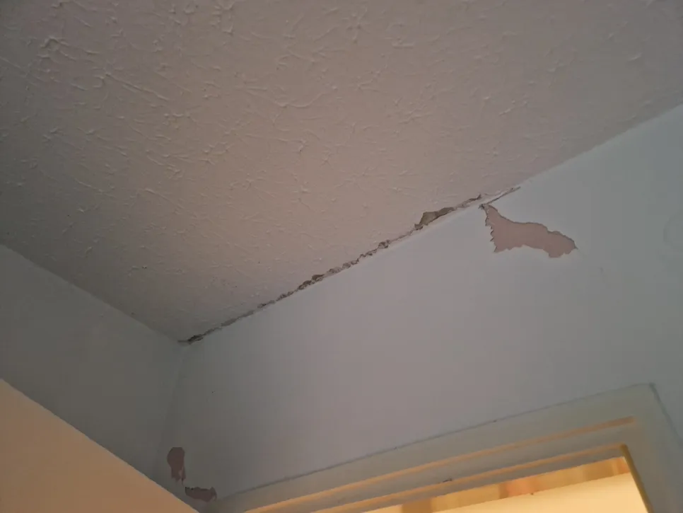 Ljuštenje boje u kutu stropa ukazuje na moguću nakupljanje vlage i propadanje žbuke.