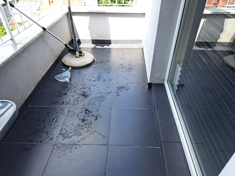Water stains visible on dark tile balcony, possible drainage issue or leakage concern.