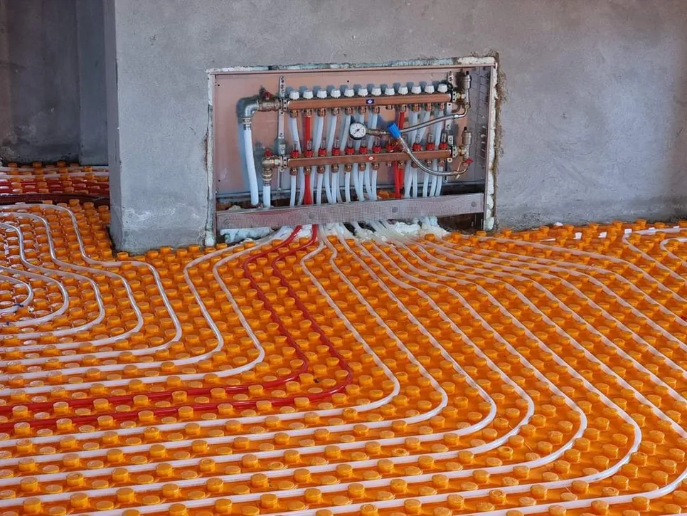 Instalacija radijantnog sustava podnog grijanja s vidljivim cijevima i komponentama razdjelnika.