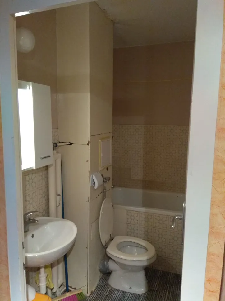 Small bathroom with cramped fixtures including a sink, toilet, and bathtub, highlighting space optimization issues.