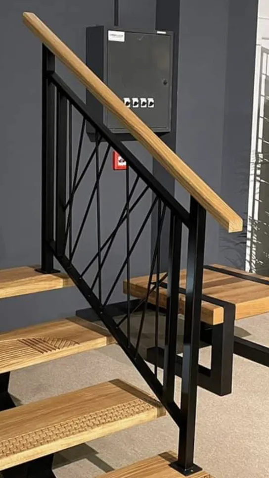 Suvremene stepenice s drvenim stubovima i elegantnom crnom metalnom ogradom za moderne interijere.