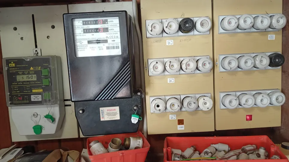 Residential electrical panel with multiple fuses, meters, and components organized for monitoring power usage.