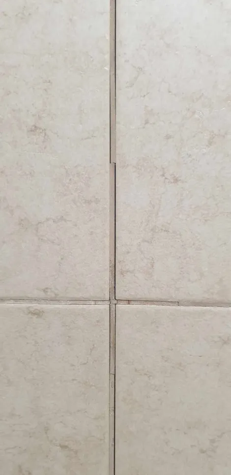 Kratak pregled pločica na zidovima kupaonice s pukotinama u fugama koje ukazuju na moguću štetu.