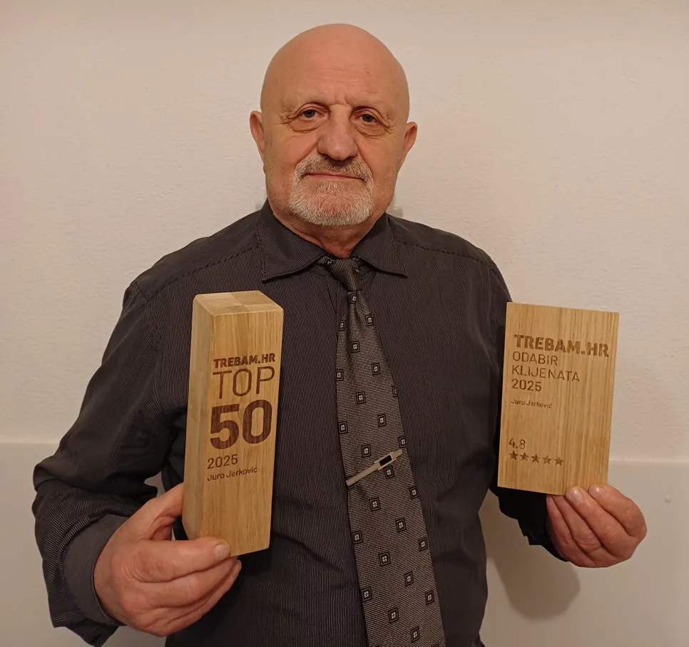 Juro Jerković stoji ispred bijelog zida i drži dvije drvene plakete. U desnoj ruci drži nagradu na kojoj piše "TREBAM.HR TOP 50 2025 Juro Jerković", a u lijevoj "TREBAM.HR ODABIR KLIJENATA 2025 Juro Jerković 4.8" sa zvjezdicama.