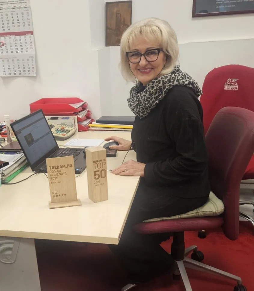 Zlatica Tilhof za svojim radnim stolom s priznanjima Trebam.hr TOP 50 i Odabir klijenata 2025., potvrđena kao jedna od 50 najboljih u svojoj djelatnosti.
